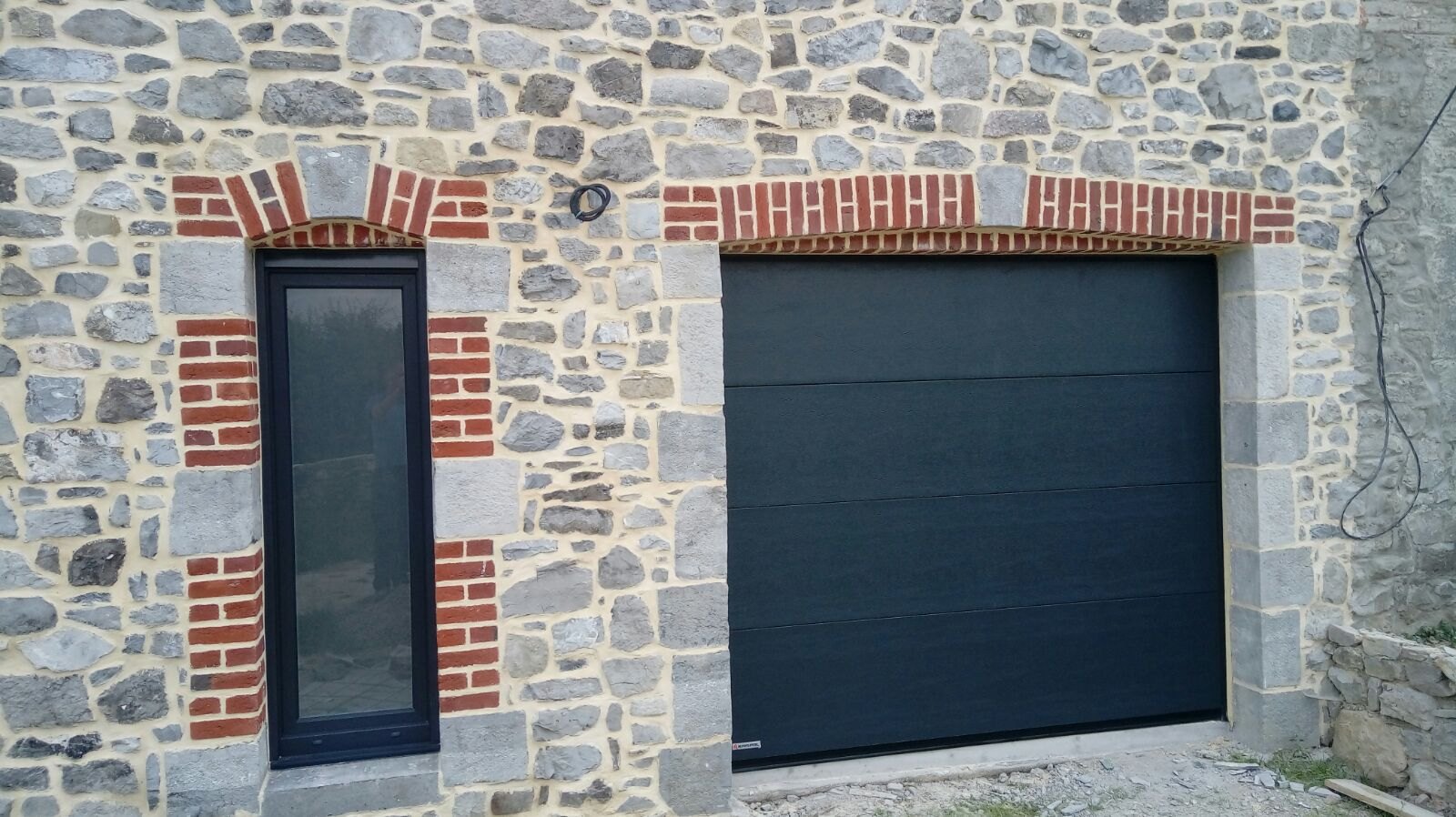 Porte sectionnelle anthracite sur façade en pierre