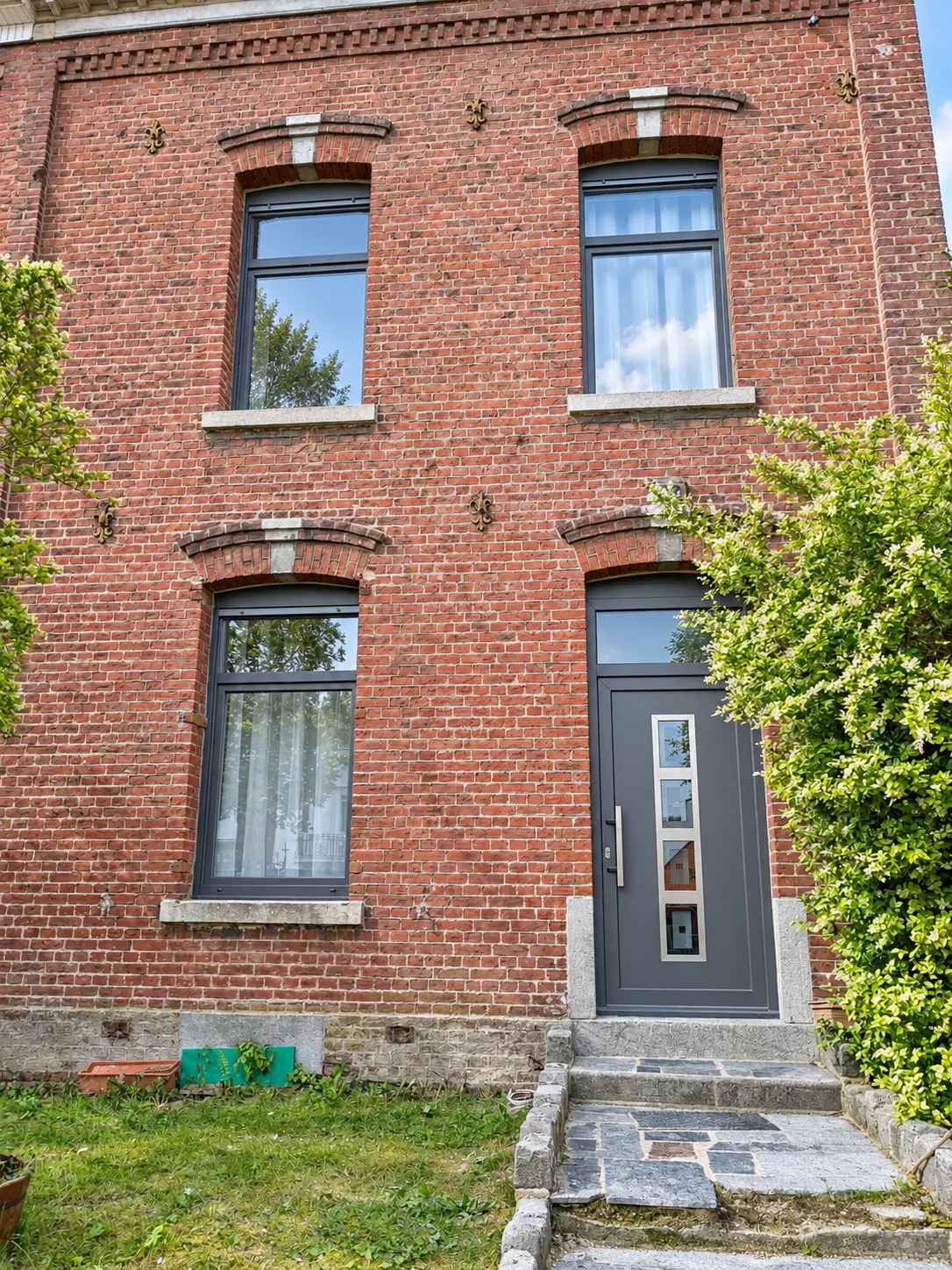 Façade en brique avec fenêtres à imposte et porte aluminium anthracite