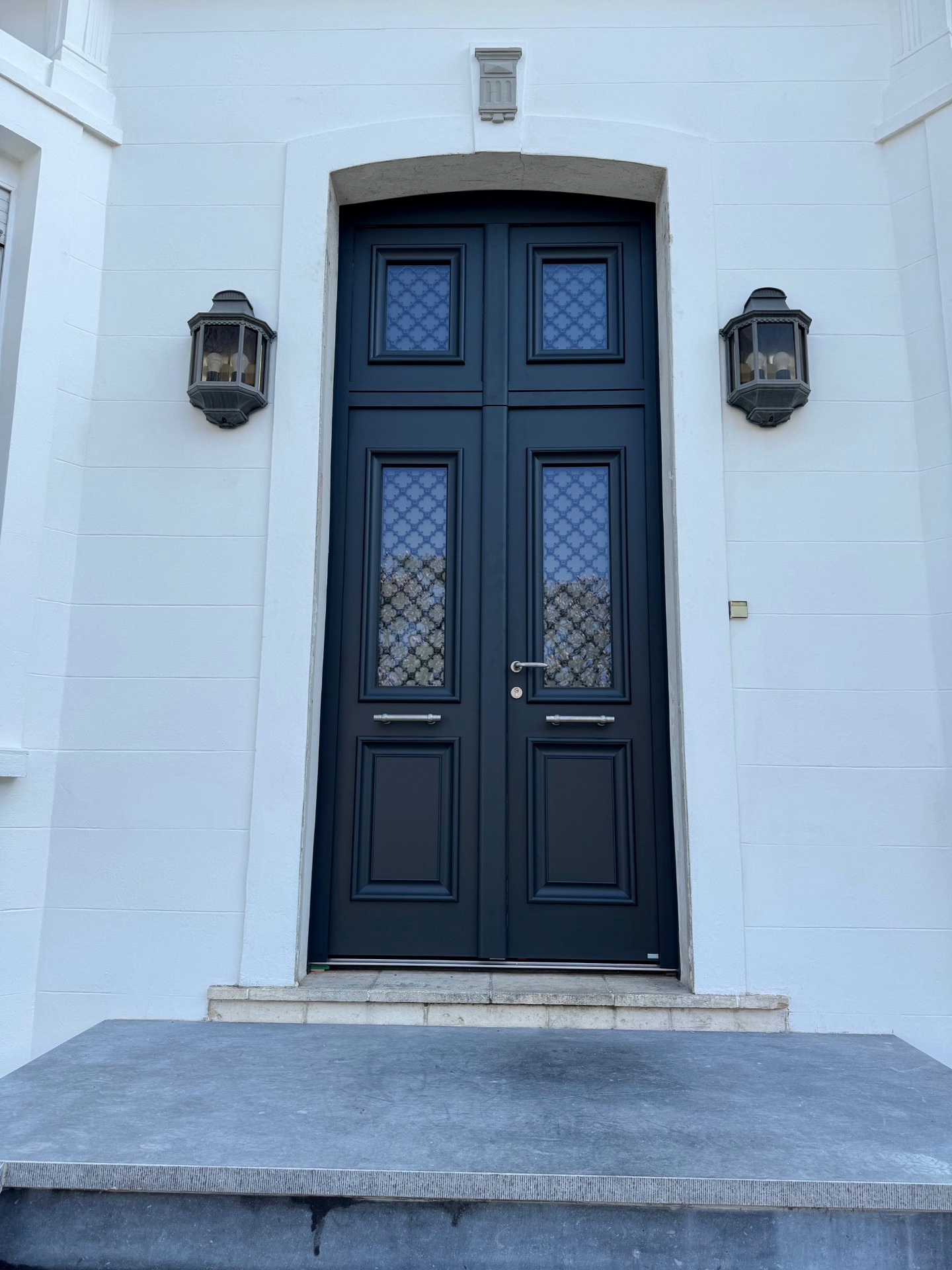 Vue rapprochée d'une porte d'entrée à double vantail avec quatre vitrages décoratifs