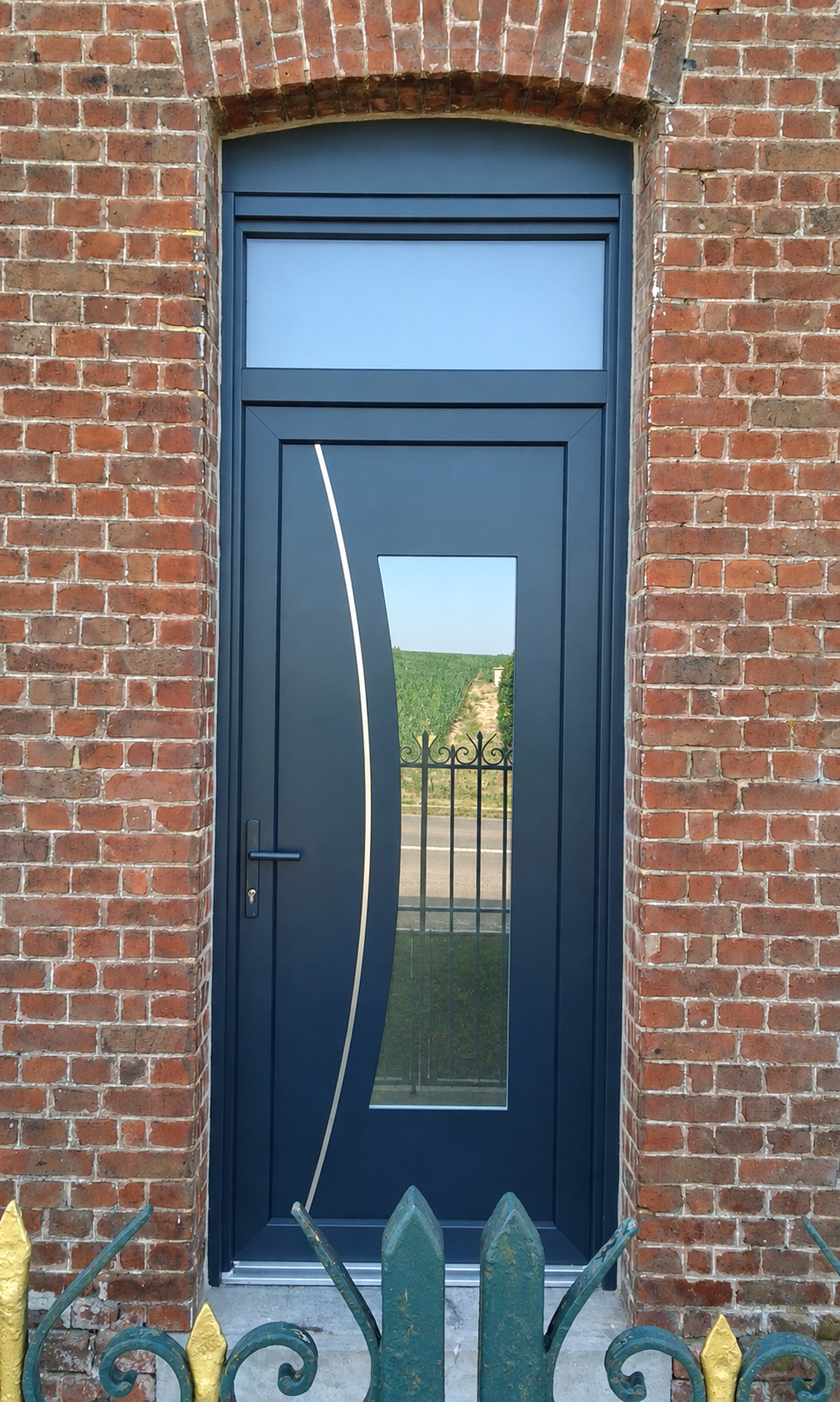 Porte d'entrée anthracite vitrée sur façade en briques