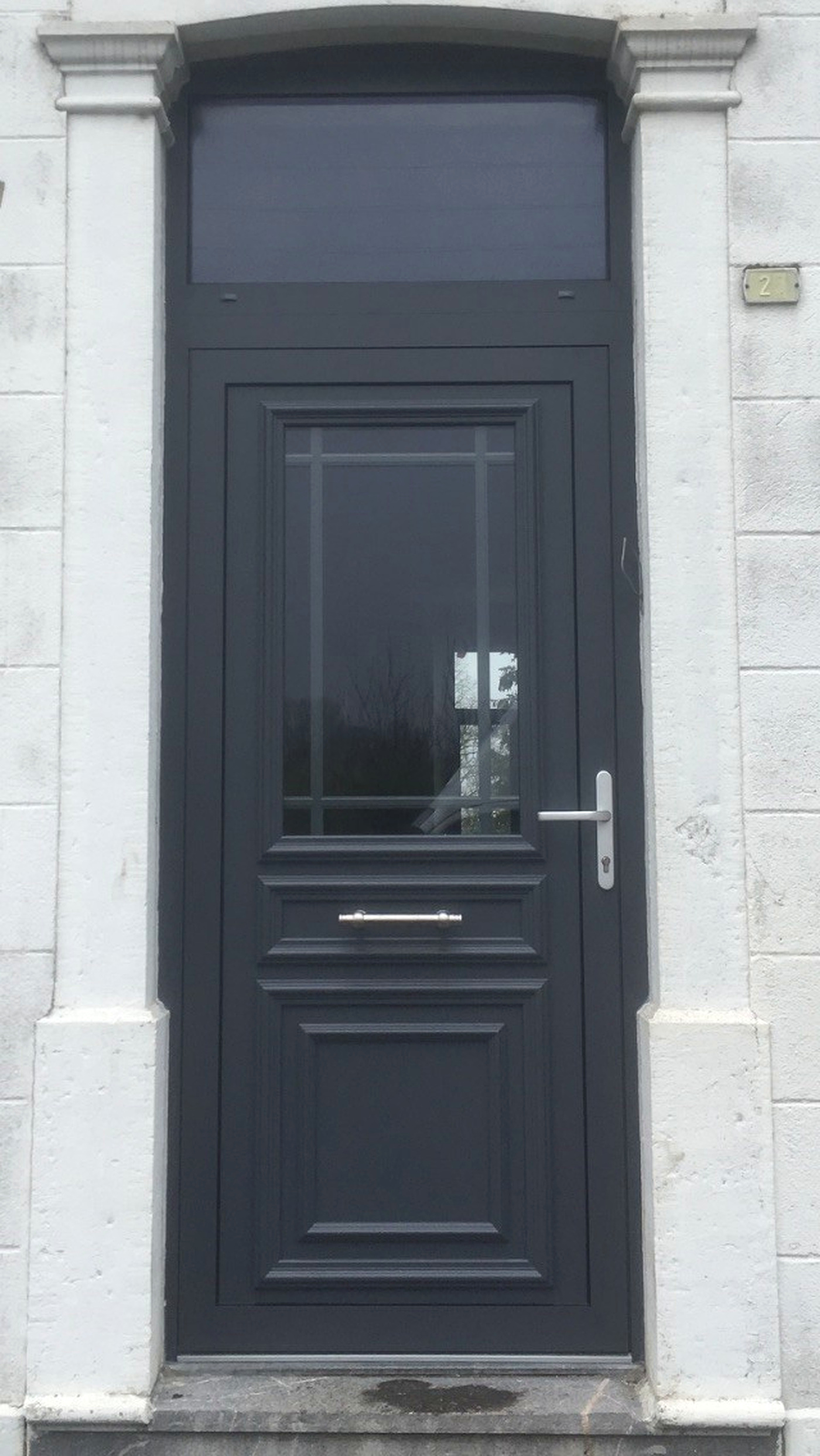 Réalisation VITREC d'une porte d'entrée anthracite moulurée avec vitrage et imposte sur façade blanche
