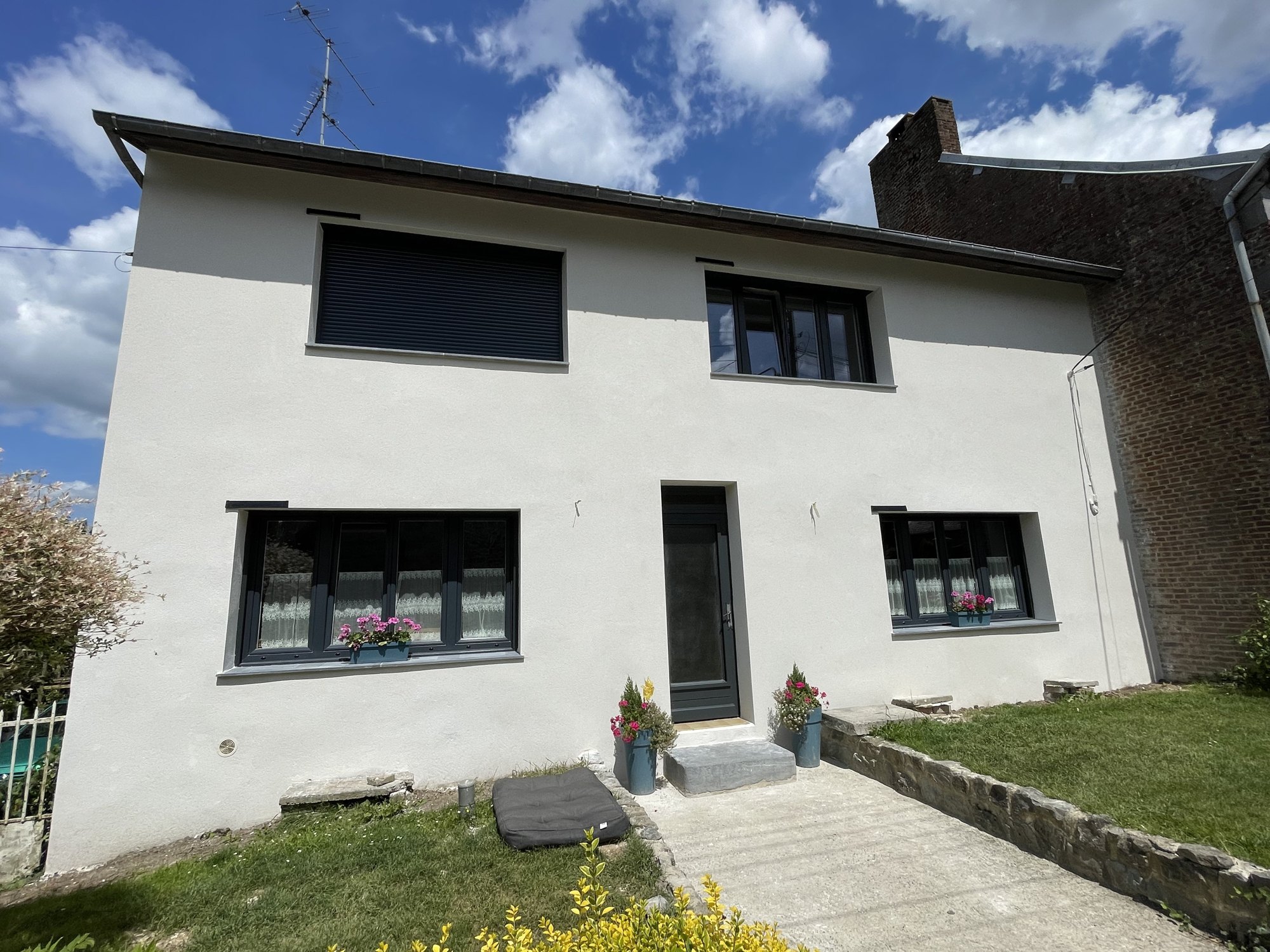 Maison enduite blanche avec fenêtres PVC anthracite et volet roulant