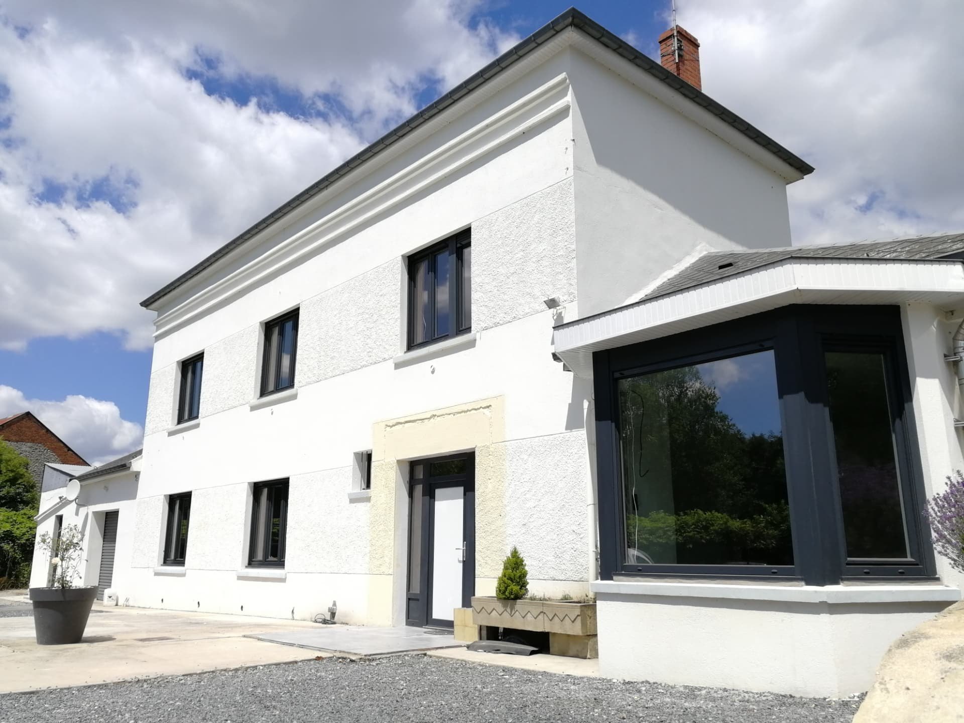 Maison blanche avec fenêtres aluminium anthracite et grande baie en angle