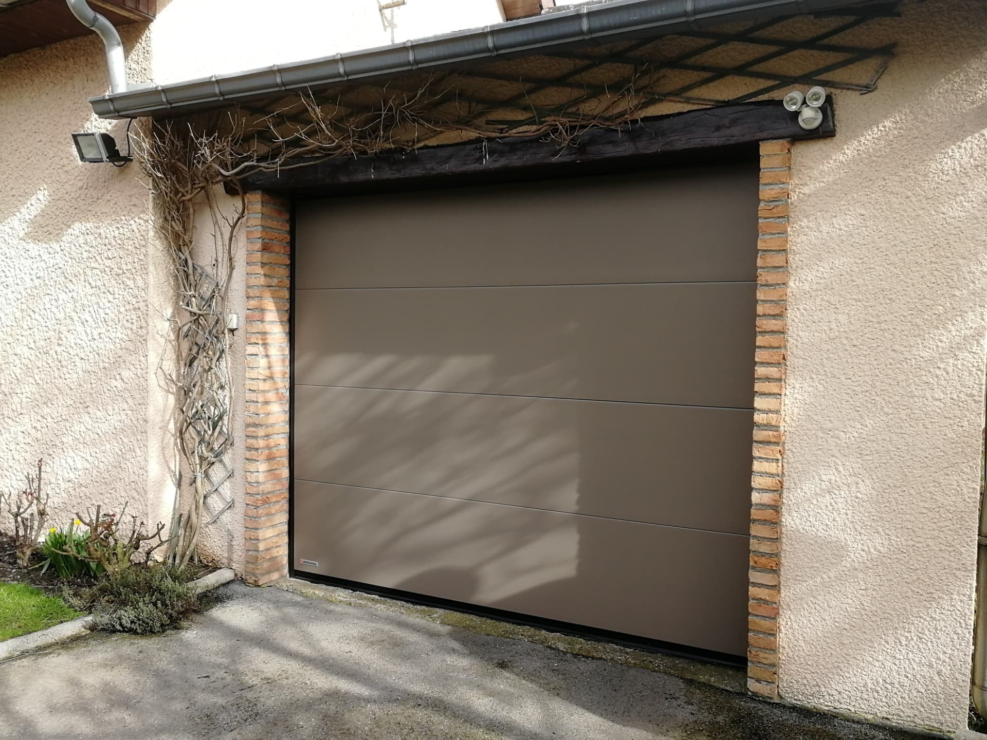 Porte sectionnelle taupe sur façade enduite