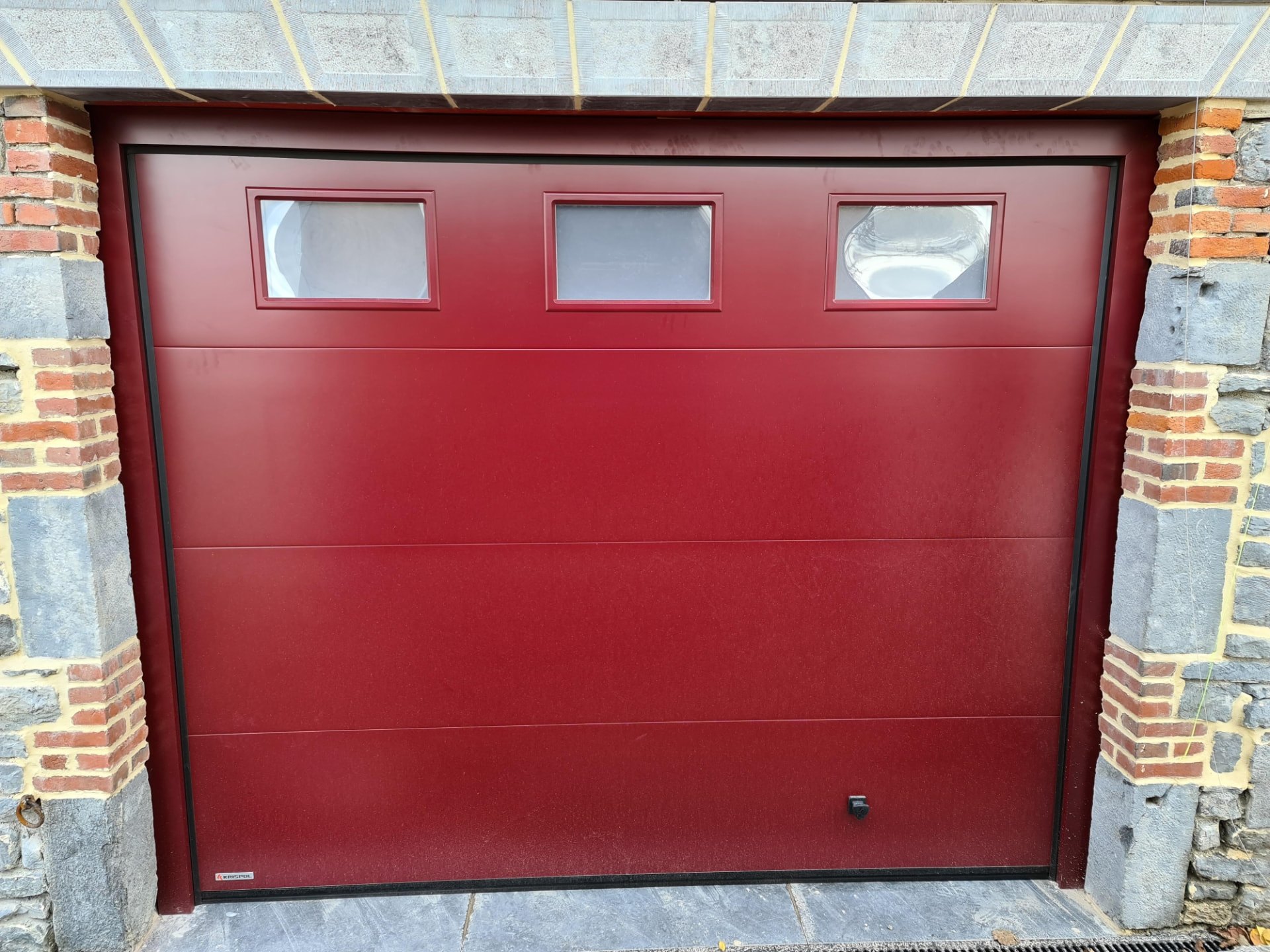 Porte de garage bordeaux avec trois hublots