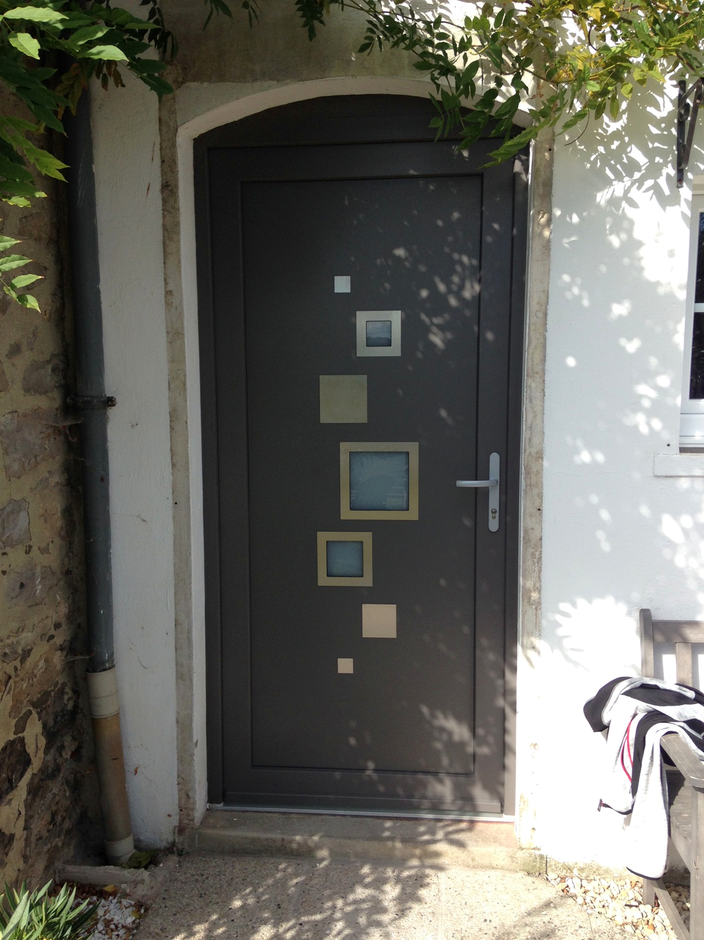 Réalisation VITREC d'une porte d'entrée anthracite avec vitrages carrés et inserts décoratifs