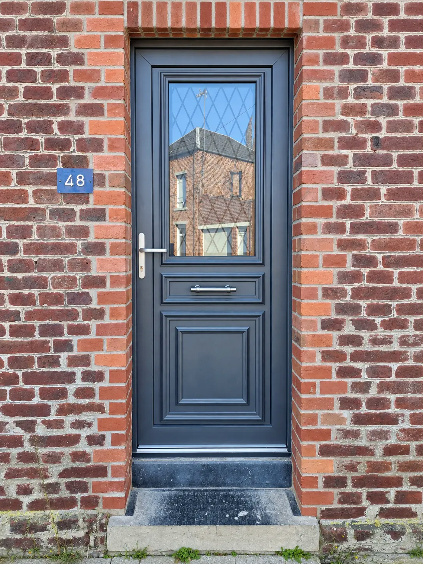 Porte bleu ardoise à croisillons sur façade en briques