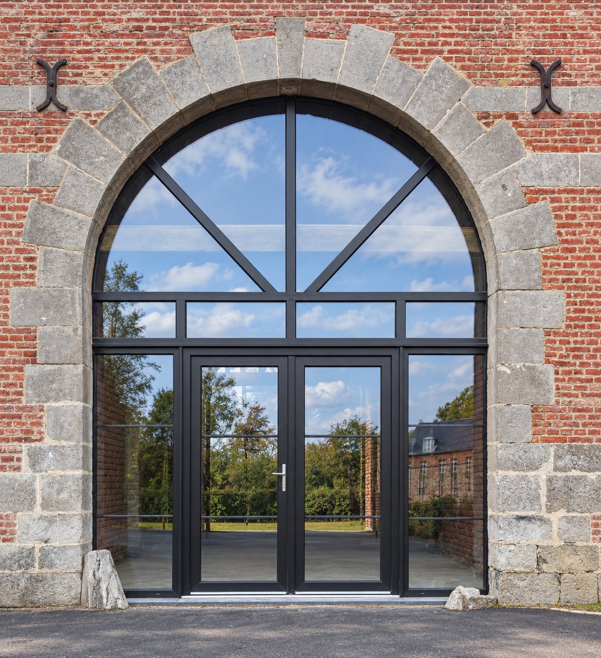 Grande verrière cintrée aluminium noir sous arche en pierre