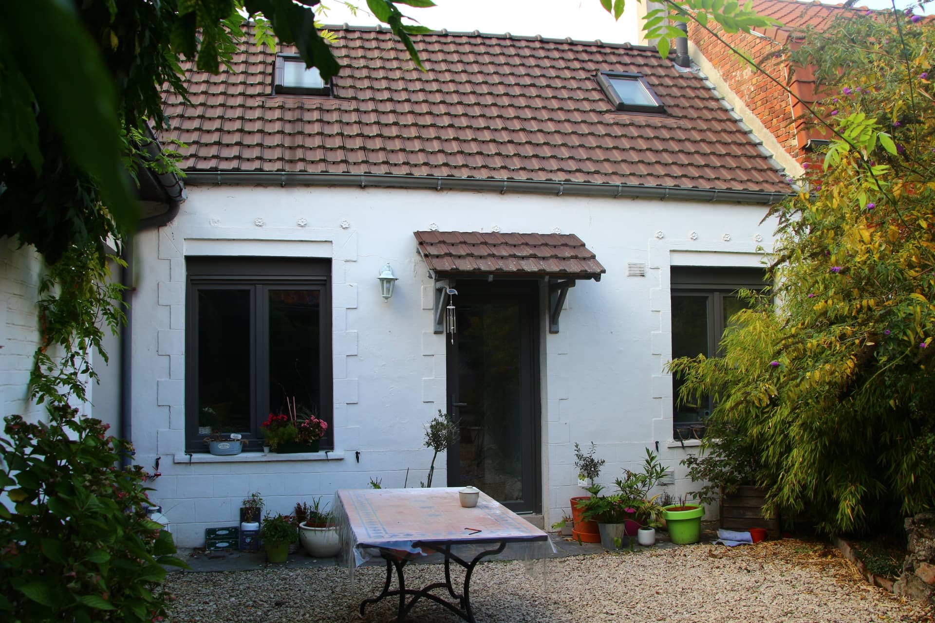 Petite maison blanche avec fenêtres et porte vitrée aluminium gris