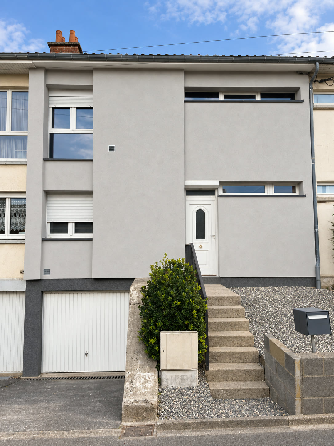 Maison de ville avec crépi gris clair et soubassement sombre