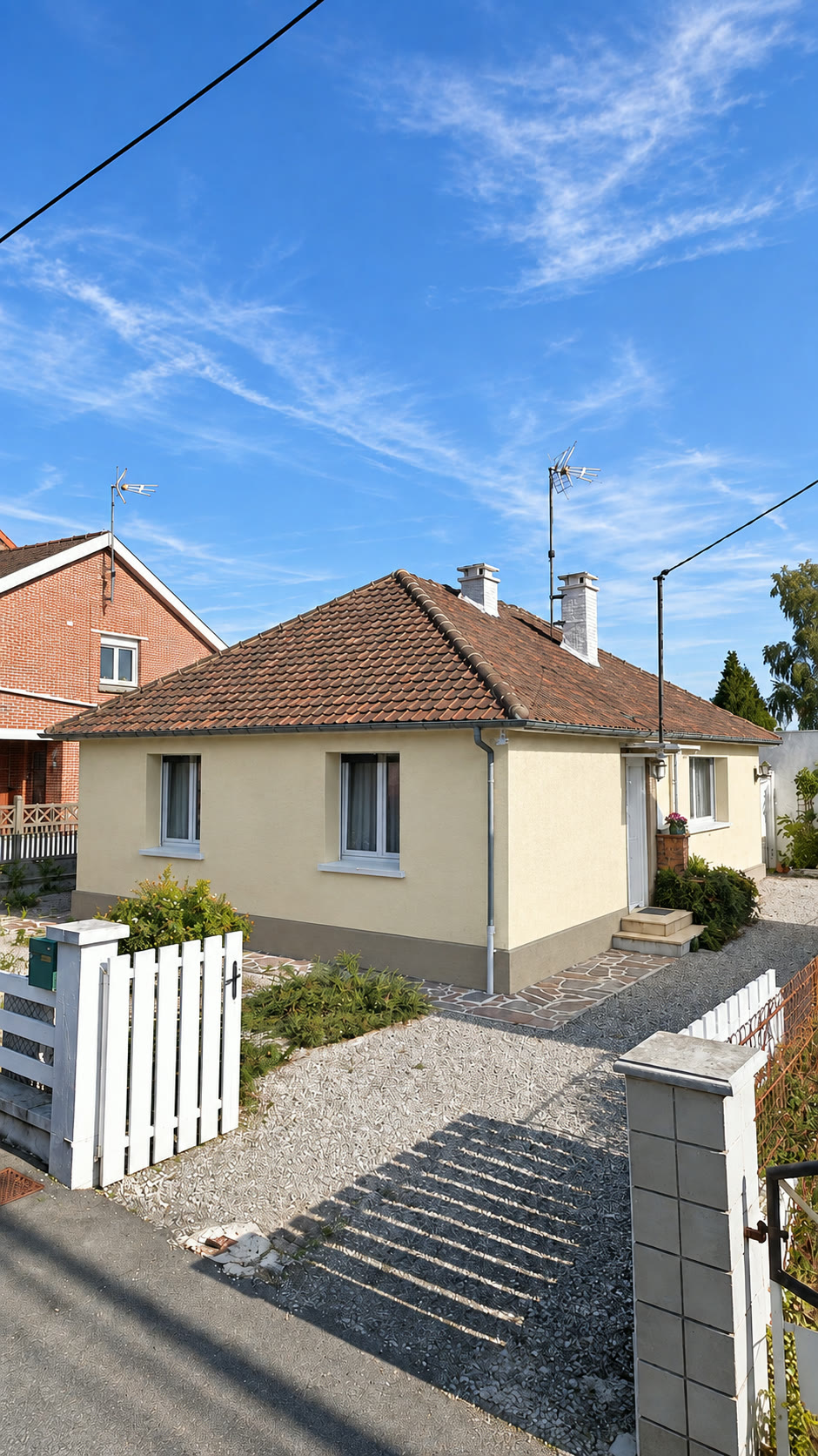Plain-pied isolé en enduit crème avec soubassement gris et toiture en tuiles